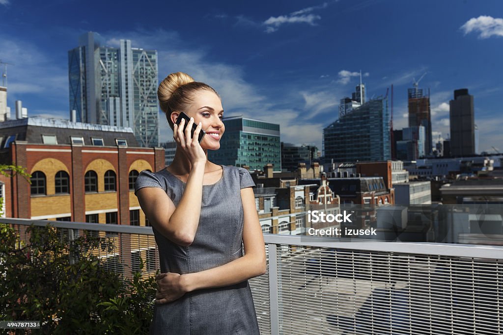 Attractive Businesswoman on the phone Portrait of professional businesswoman standing against cityscape and talking on phone. Adult Stock Photo