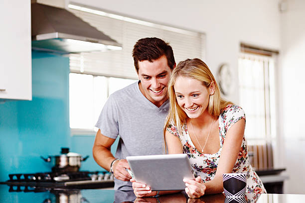 istock Smiling couple in kitchen look  down at digital tablet screen 494787345