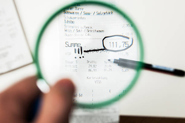 Man looking through a magnifying glass at receipt Paris, France - January 14, 2015: Man looking through a magnifying glass to receipt from grocery store with the total amount of more than 100 euros - the sum is marked with exclamation signs lens pas de calais stock pictures, royalty-free photos & images