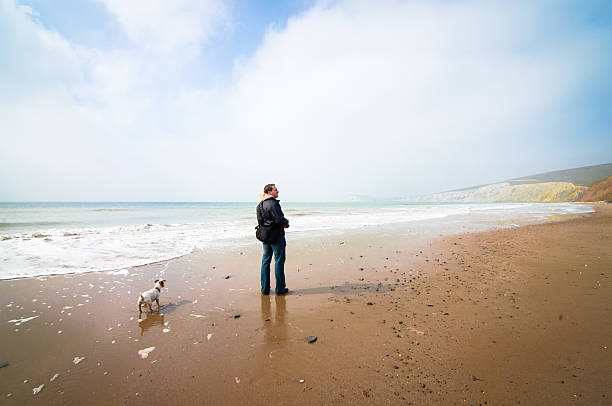 istock Man walking on the beach with his dog 494809665
