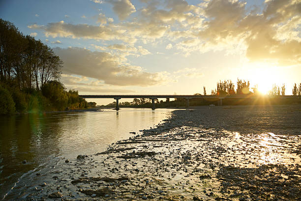 Manawatu River Photo taken of the Manawatu River in Manawatu region by Ashhurst (New Zealand) during a sunset. View looking down river towards the Ashhurst bridge during a sunset with bush on the left and shingle shore on the right of the river, blue sky and clouds. manawatu river stock pictures, royalty-free photos & images