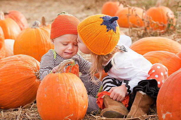 istock Sad Baby Brother Getting Kiss From Sister In Pumpkin Patch 494810556