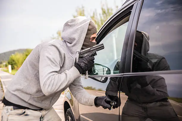 Robber pointing a gun at a driver