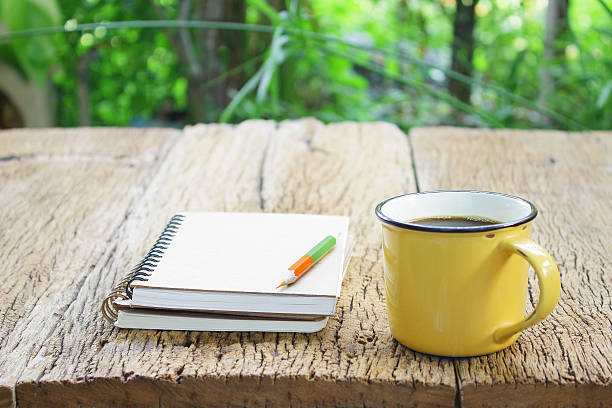 istock Notebook  and coffee in yellow cup on wooden table 494826126