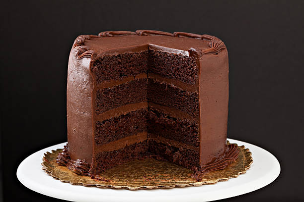 Chocolate Fudge Cake With Slice Missing A close up, horizontal, isolated on black photograph of a multi layered chocolate fudge cake with a slice missing. chocolate cake photos stock pictures, royalty-free photos & images