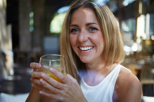 istock Female smiling while drinking a glass of fresh orange juice 494829630