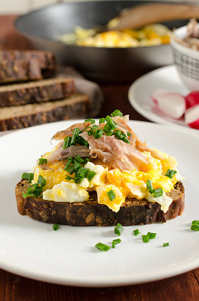 Smorrebrod - danish sandwich on rye bread with scrambled eggs and smoked mackerel