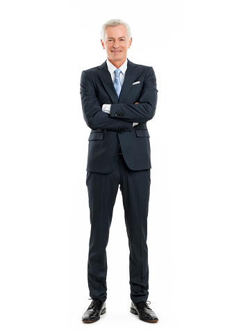 Full length portrait of senior businessman standing against white background with arms crossed.