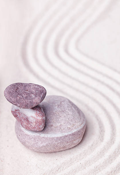 istock Stack of purple quartz and beige stones in the sand 494830608