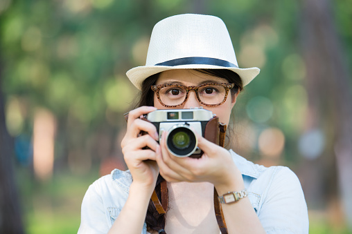 Beautiful asian girl smiling with retro camera photographing, outdoor travel