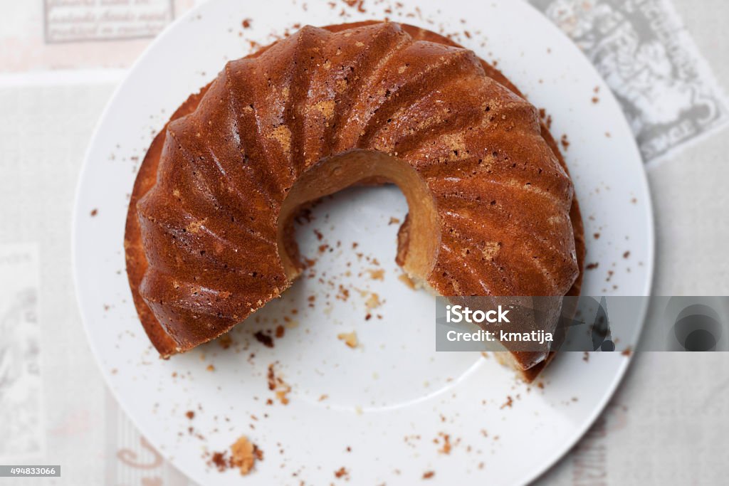 Take a piece Baked roll with a missing piece laying on a ceramic plate on a table. 2015 Stock Photo