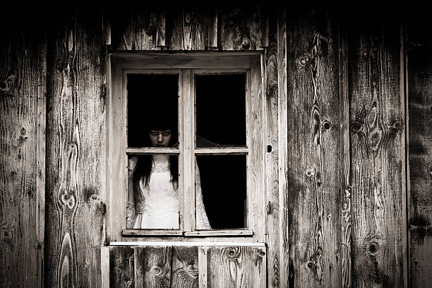 Portrait of a woman in evening dress. She stands at a window of the staircase at night. She is illuminated only by light from a street lamp. She is smoldering in memories.