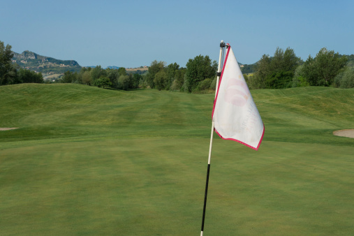a golf flag in a course and a blue sky