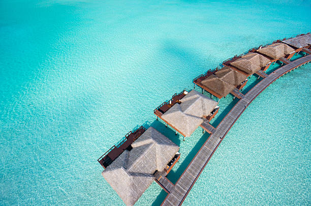 close aerial overtware bungalows in lagoon close aerial view of luxury overwater villas in tropical lagoon jetty aerial stock pictures, royalty-free photos & images