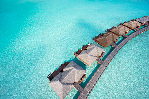 close aerial overtware bungalows in lagoon close aerial view of luxury overwater villas in tropical lagoon maldives stock pictures, royalty-free photos & images