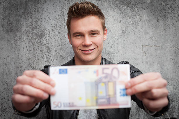 Attractive young guy holding fifty euro note stock photo