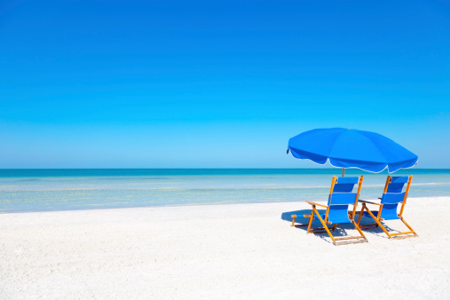 Two blue beach loungers and umbrella at white sandy beach
