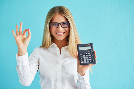 Young business woman show calculator and gesture ok