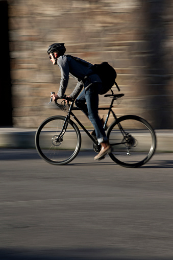 A male bike messenger rides along a busy street on a sunny morning.