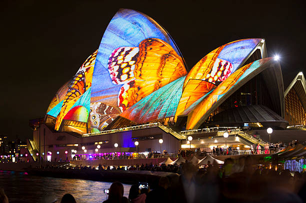 Sydney, Australia - June 18, 2016: Boats creating light trails pass the Sydney Harbour Bridge, lit up in colourful lights as part of the Vivid Sydney festival.