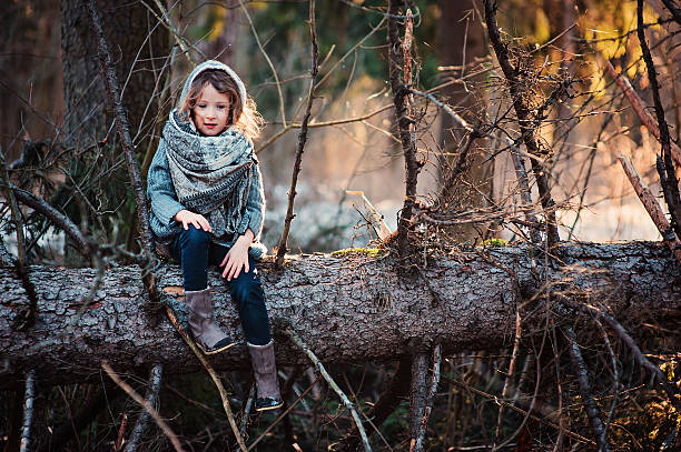 istock child girl sitting on old pine tree on winter walk 494879882