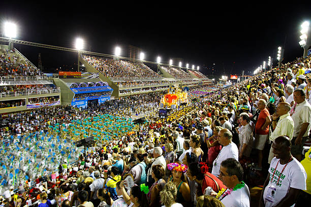 Rio de Janeiro, Brazil - February 19, 2012: Tourists watching the samba school parade in Sambodrome in Rio de Janeiro carnival. This is one of the most waited big event in town and attracts thousands of tourists from all over the world. The parade is happenning in two consecutive days and the samba schools are always trying their best to impress the judges. Every samba school have a bit more than one hour limit to do his presentation through the seven hundred meter avenue.