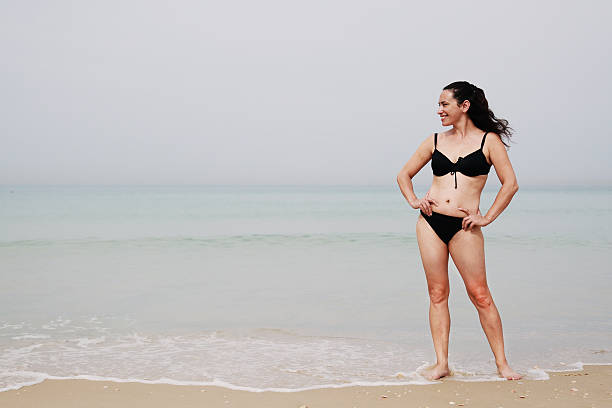 istock beautiful woman standing on the beach 494880372