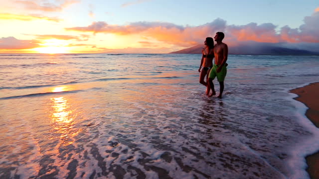 Happy Young Romantic Couple Walking on the Beach Enjoying the Sunset