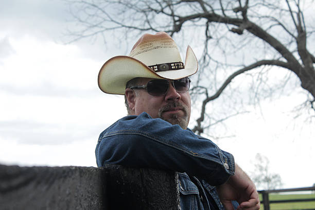 istock Man Wearing Cowboy Hat and Sunglasses Poses For Camera 494891848