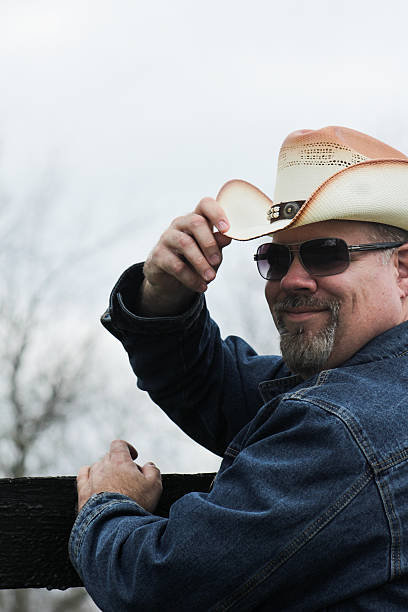 istock Man Grins While Touching Brim of Cowboy Hat 494893406