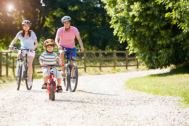 Asian Family On Cycle Ride In Countryside Asian Family On Cycle Ride In Countryside Cycling Towards Camera family asian ethnicity couple child stock pictures, royalty-free photos & images