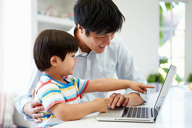 istock Asian Father Helping Son To Use Laptop At Home 494897101