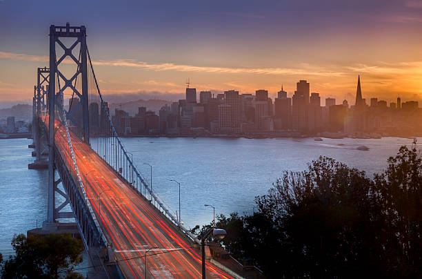 zatoka most i san francisco panoramę miasta o zachodzie słońca - bay bridge car traffic transportation zdjęcia i obrazy z banku zdjęć