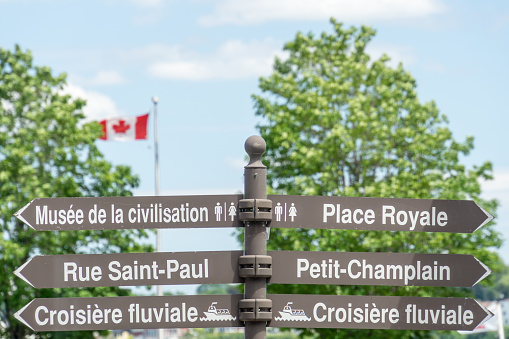 Quebec City, Canada - 18 June 2015 - A street sign with directions to popular tourist destinations within Quebec City and a Canadian flag in the background