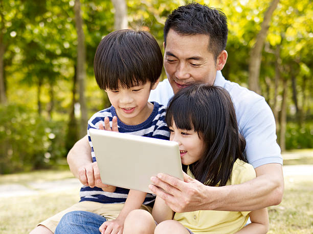 istock asian father and children using tablet outdoors 494906108