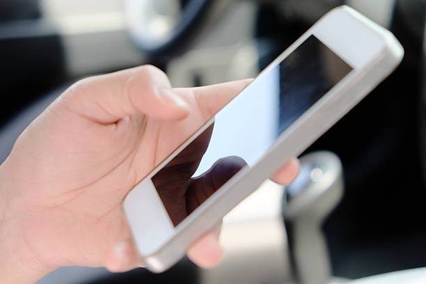 istock Young woman holding mobile device in the car 494906410