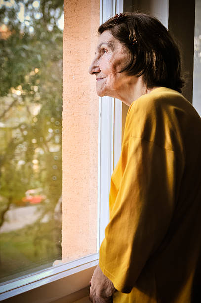 istock Solitude - senior woman looking through window 494906944