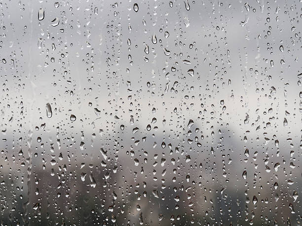 istock Raindrops trickling down window in front of blurred city skyline 494928618