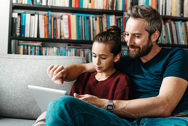 istock bearded father with daughter tapping at digital tablet on couch 494941000