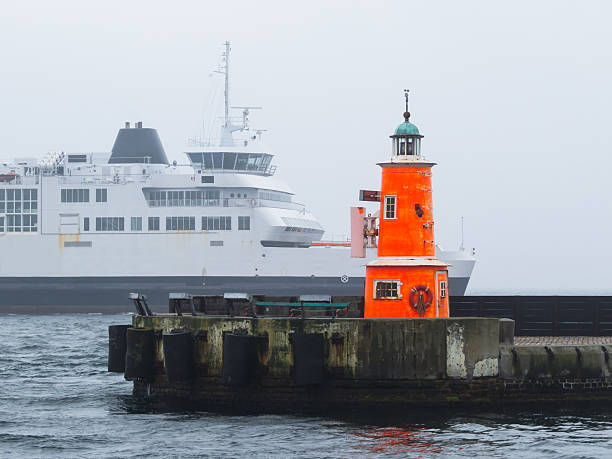 istock Orange lighthouse and ferry passing in a fog 494949146