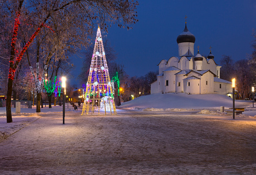 Night view of Christmas and New Year decorations in public garden near church in Pskov, Russia