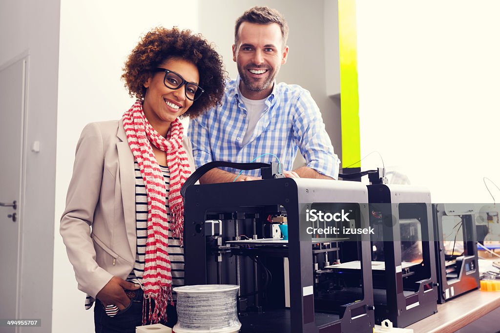 3D printer office Two business colleagues standing next to 3d printer machines and smiling at the camera. 3D Printing Stock Photo