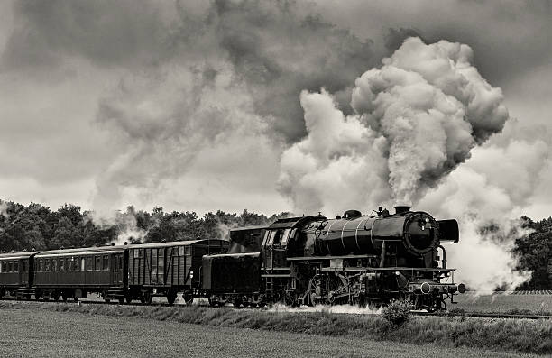 Steam Train Old steam train pulling railroad cars driving through the countryside. Black and white image. road going steam engine stock pictures, royalty-free photos & images