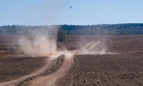 May ploughed field and dust tornado moving across the wheel track.