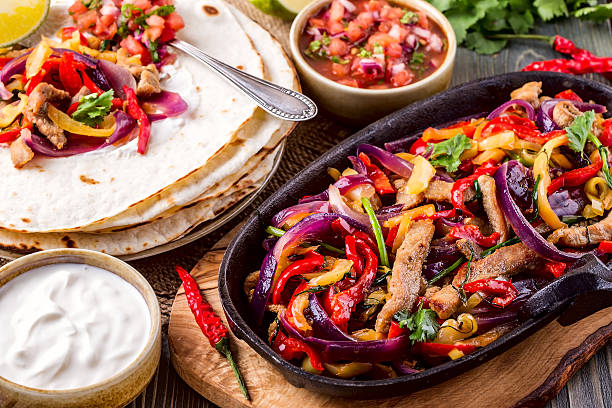 Pork fajitas with onions and colored pepper, served with tortill Pork fajitas with onions and colored pepper, served with tortillas, salsa and sour cream, selective focus. fajita photos stock pictures, royalty-free photos & images
