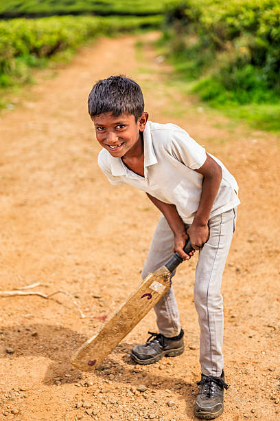 istock Young Sri Lankan boy playing cricket on tea plantation 494960058