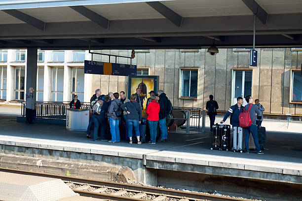 Essen, Germany - May 31, 2014: Capture of a group of travelling people standing on platform of station Essen in Ruhrgebiet. Spring day. People are standing close togetehr and are talking. In background and at right side are more passengers waiting for train.