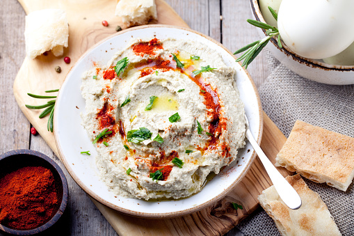 Traditional arabian eggplant dip baba ganoush with herbs and smoked paprika on a wooden background