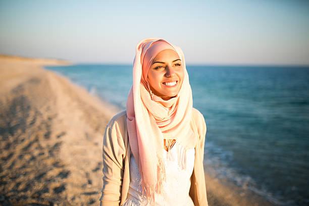 junge schöne muslimische frau glücklich am strand - arabische frau kopftuch stock-fotos und bilder