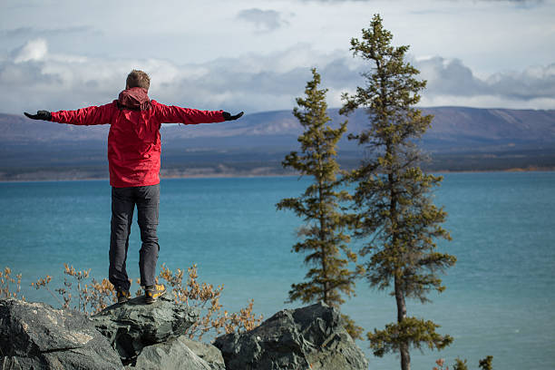 istock Cheering man standing on cliff arms outstretched 494992650